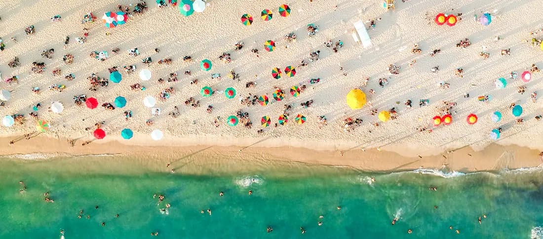 Aerial view of the beach with lots of people and colorful beach umbrellas