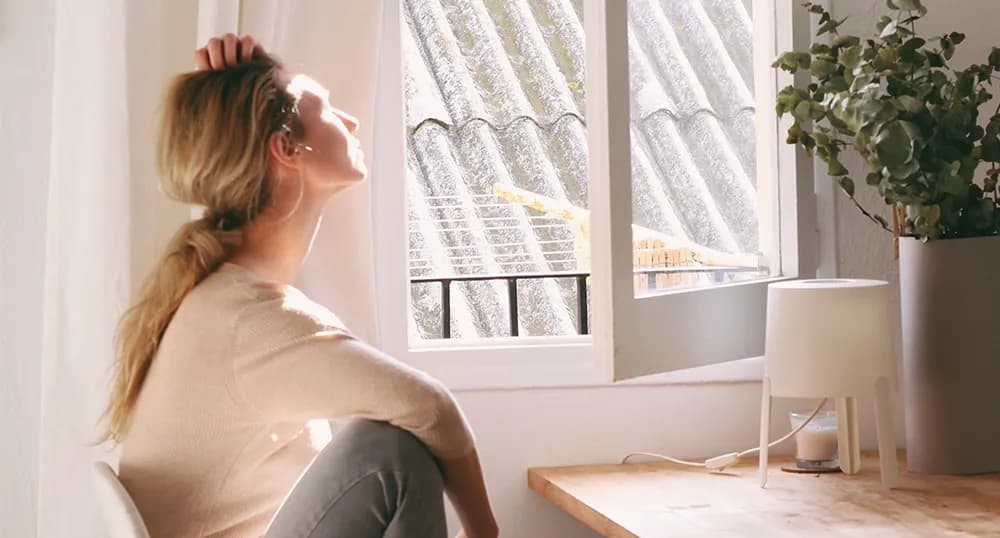 Upset woman sits by a window