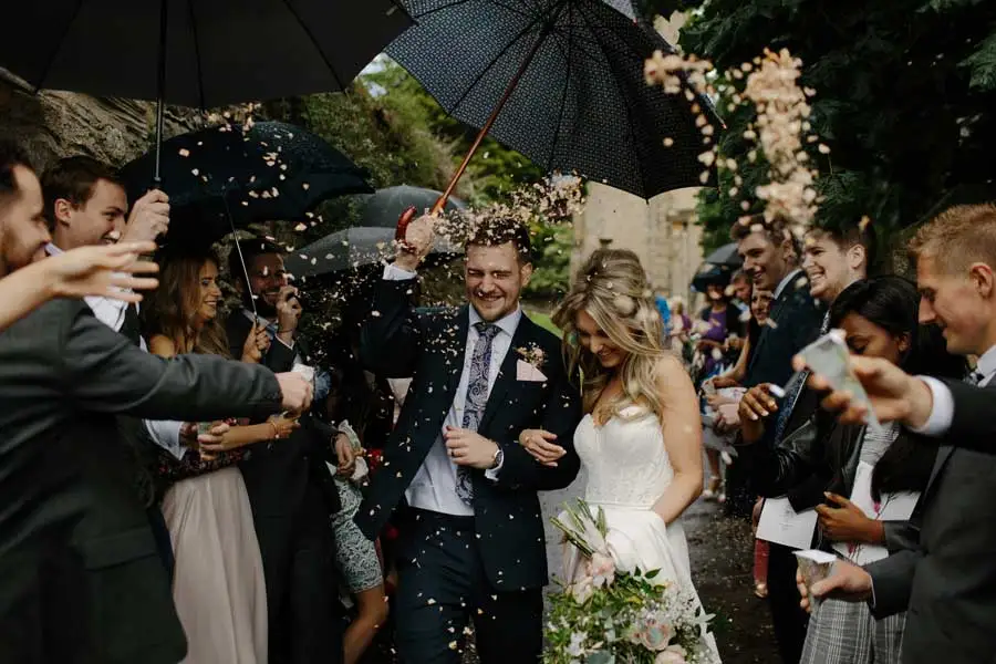 Newlyweds get flowers thrown on them by guests